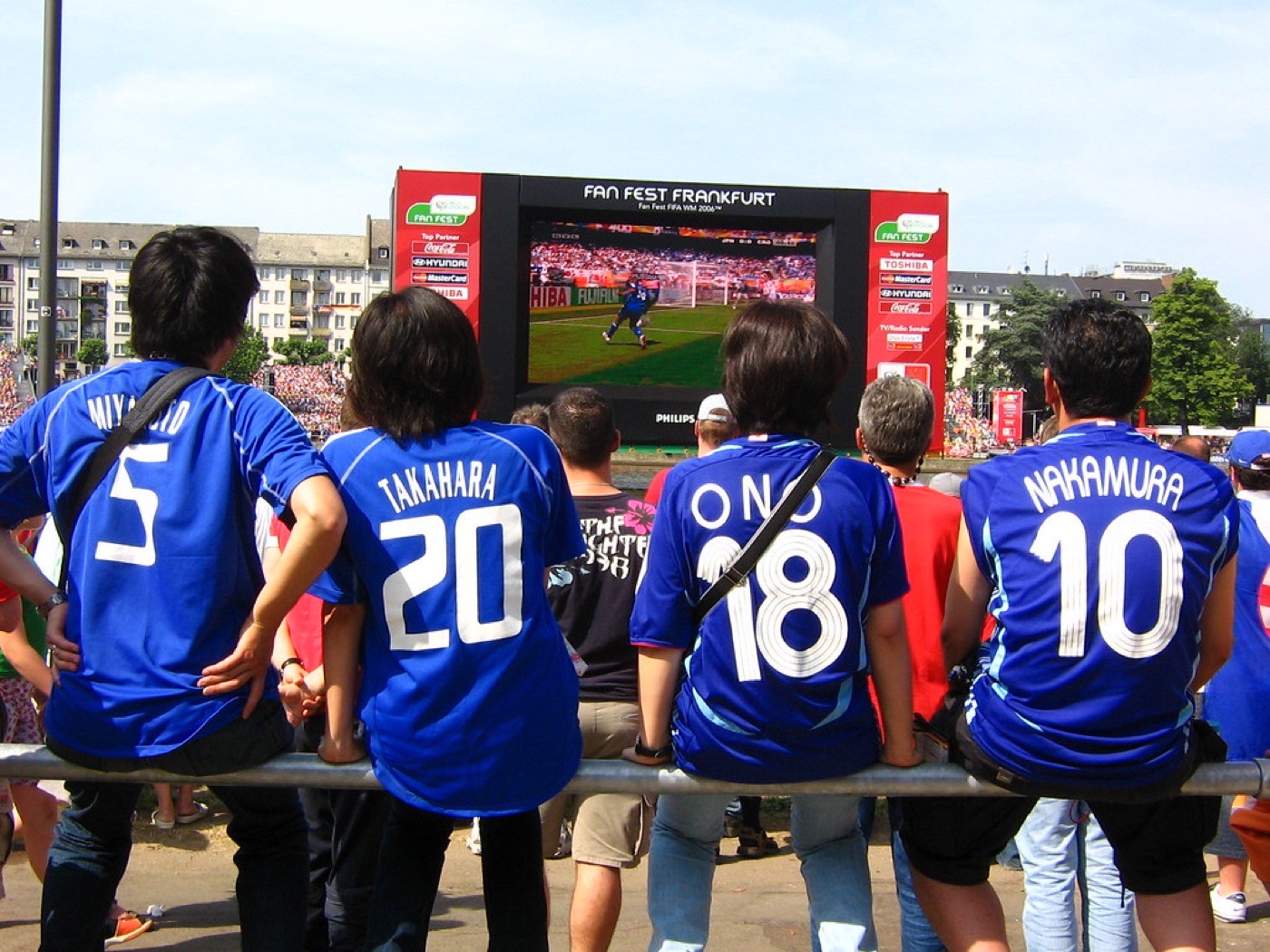 Japan fans in blue shirts watching the team at a FIFA Fan Fest